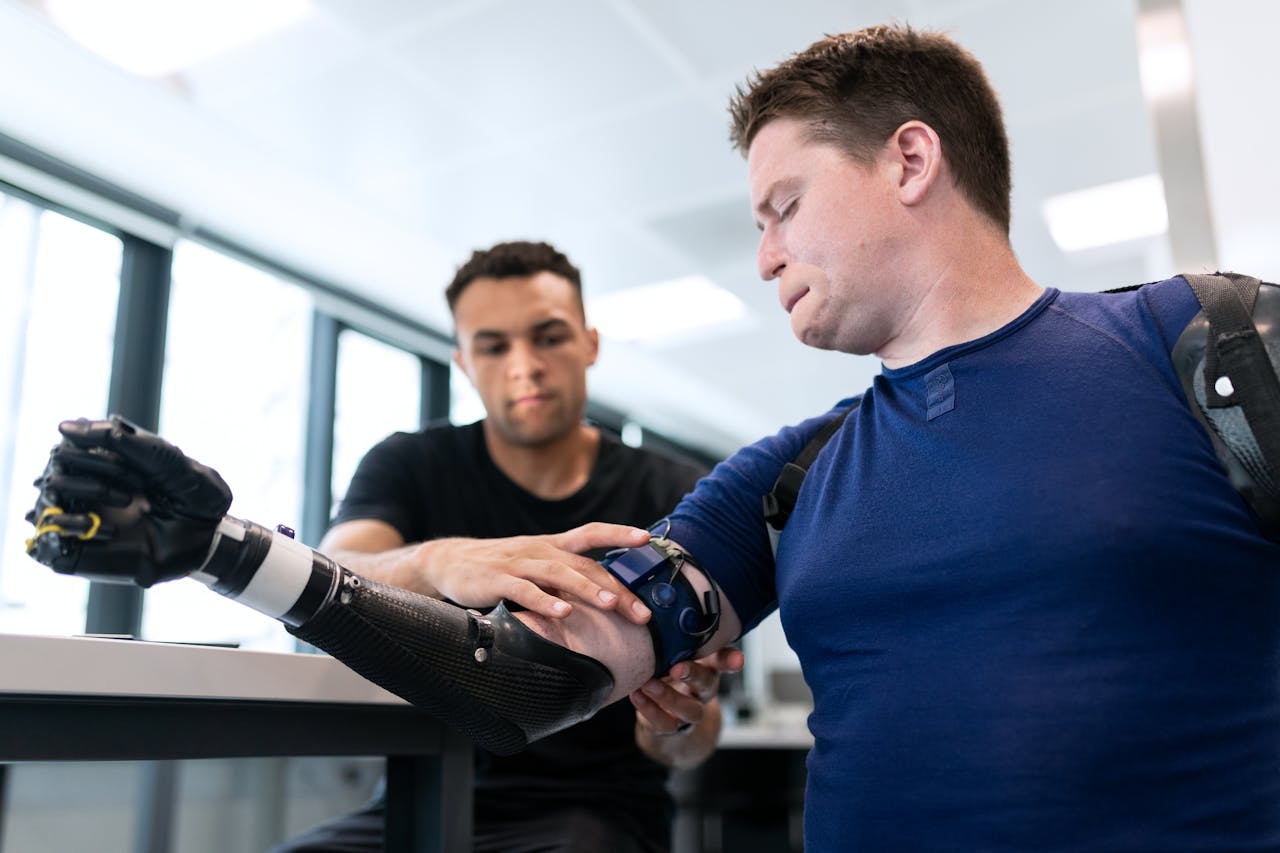 Engineer assists patient in fitting a high-tech prosthetic arm in a modern healthcare facility.